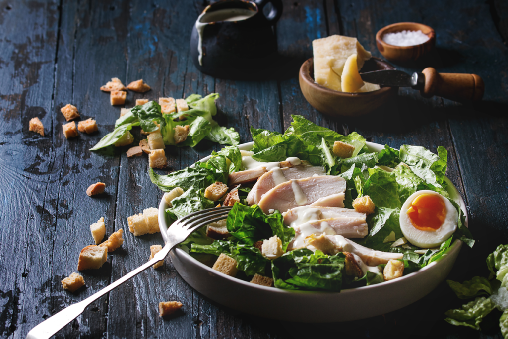 A plate of freshly prepared Chicken Caesar Salad with grilled chicken, romaine lettuce, Parmesan cheese, and homemade croutons.