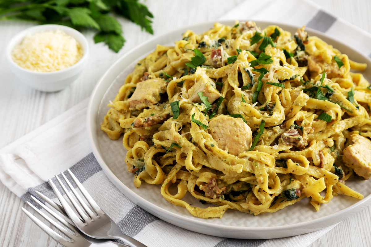 A bowl of Chicken Carbonara with creamy sauce, tender chicken pieces, and freshly grated Parmesan cheese on top.