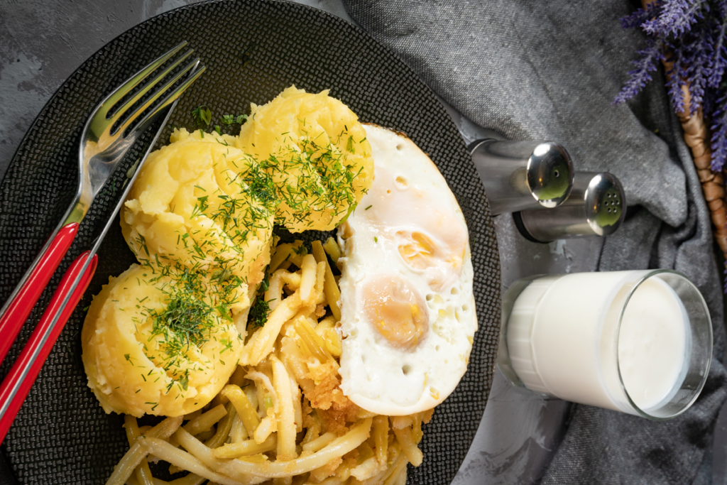 A plate of fried eggs served with boiled potatoes and fresh herbs.