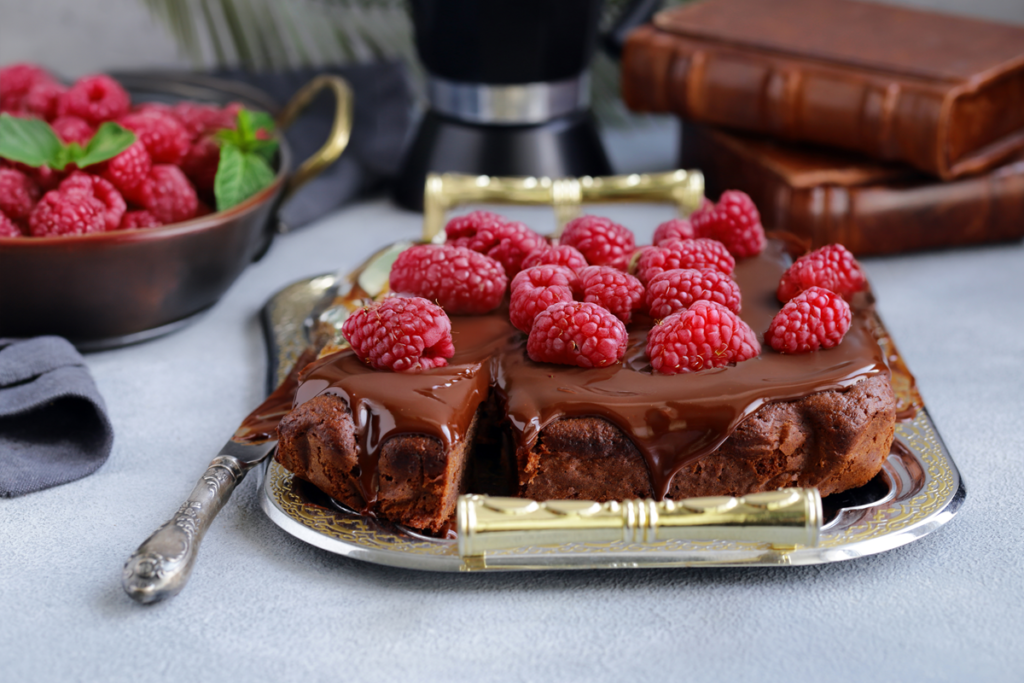 Slice of decadent raspberry cake with rich chocolate ganache dripping over the edges