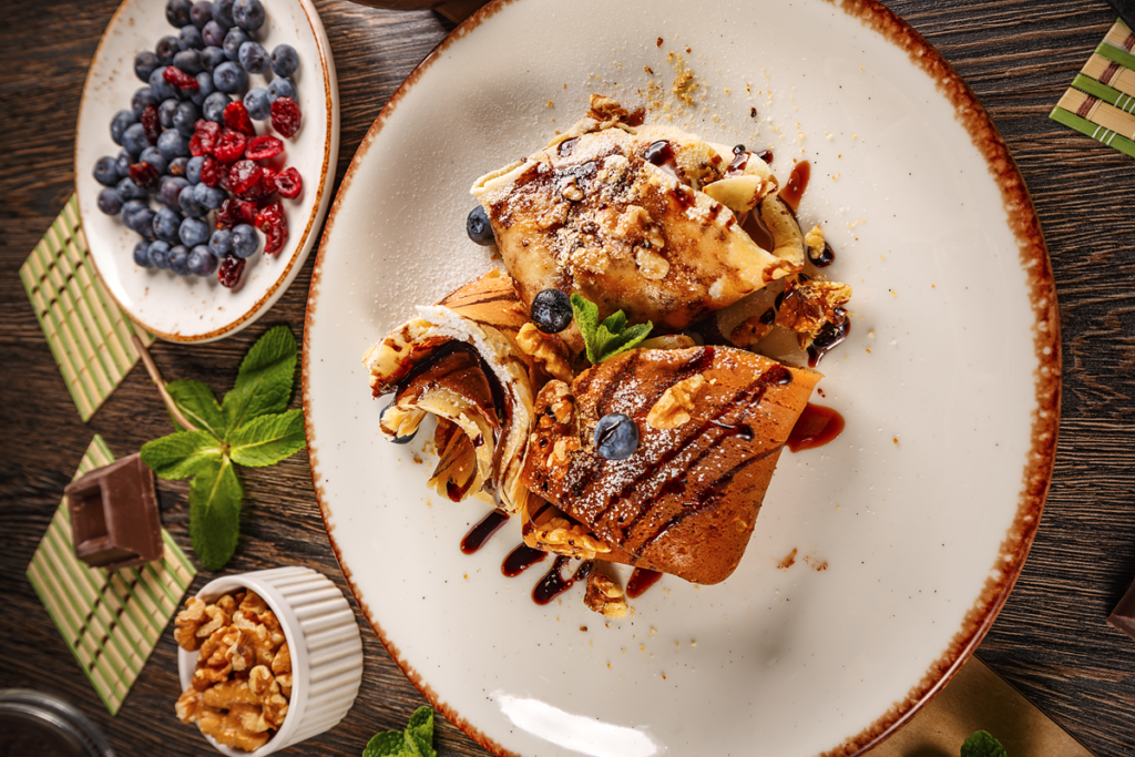 Decadent crepes with chocolate cream, garnished with blueberries and walnuts