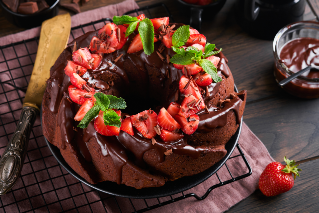 Chocolate bundt cake topped with glossy ganache icing on a serving platter.