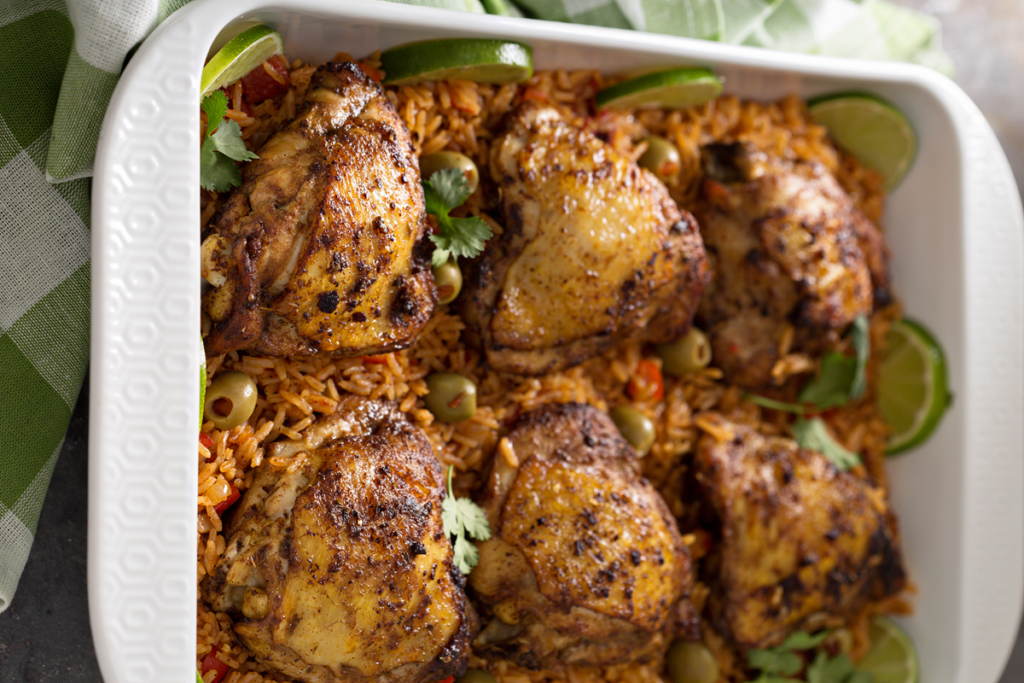 Roast chicken served with aromatic rice and herbs on a rustic wooden table.