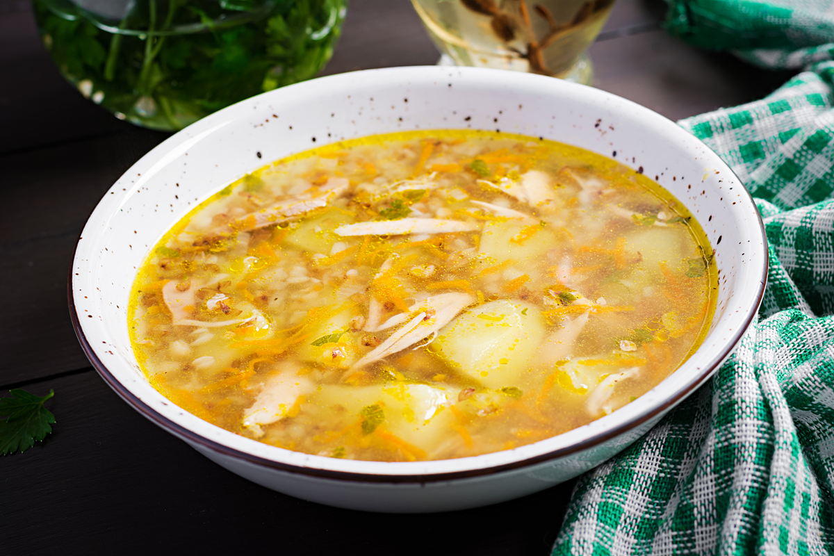 A bowl of healthy chicken potato soup with visible chunks of potatoes, shredded chicken, and a light broth.