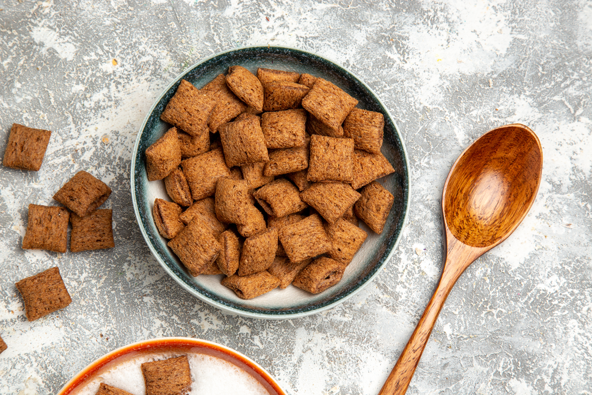 A bowl of gluten-free cinnamon toast crunch cereal with a wooden spoon on the side.