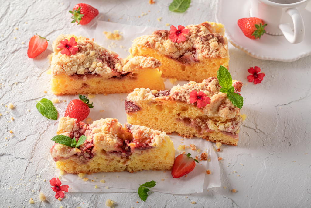 Slices of homemade strawberry crumb cake with fresh strawberries and mint leaves.