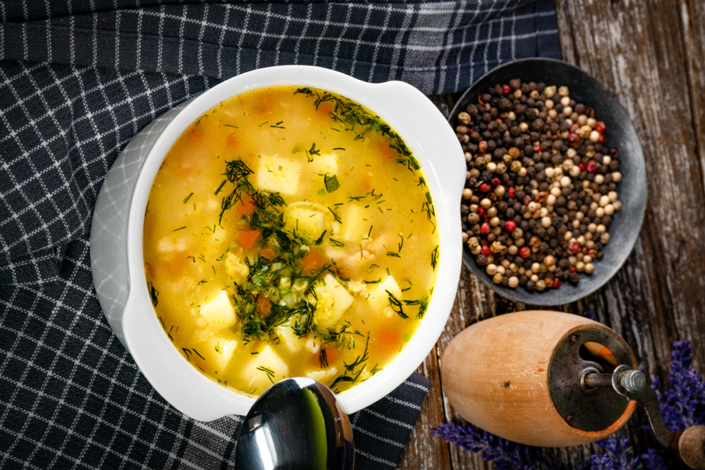 Bowl of vegetables and chicken soup with fresh herbs