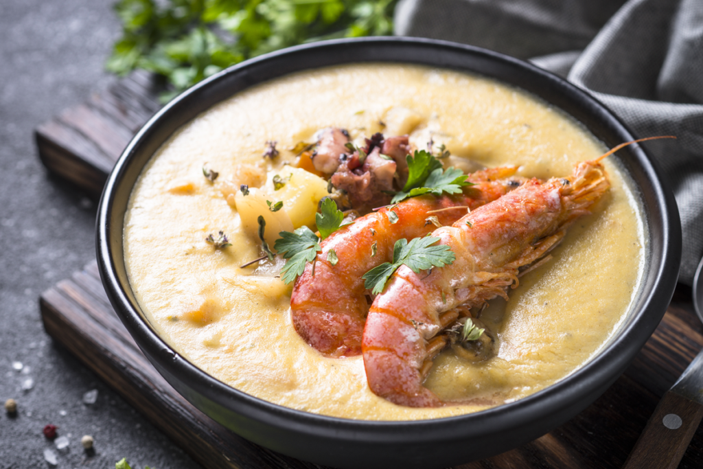 Bowl of creamy seafood chowder garnished with prawns and herbs