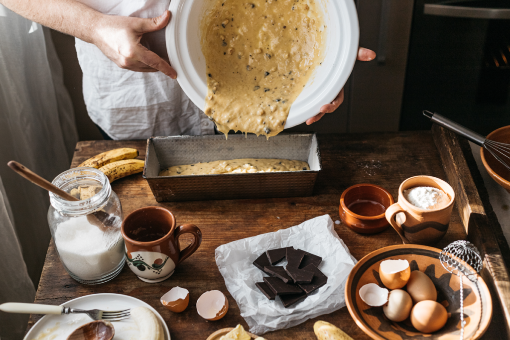 pouring banana bread batter into a loaf pan